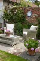 Patio dans jardin clos avec chaises en rotin et table basse, pots plantés et rosiers grimpants - Open Gardens Day, Easton, Suffolk