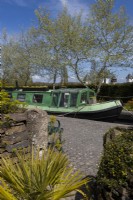Jardin de Canal Street avec une vraie barge et une écluse à côté d'une rue en terrasses avec quatre petits jardins à l'avant avec dans cette image, l'entrée d'un jardin de cottage. Trago Mills montrent les jardins, Devon, Royaume-Uni. Peut. Printemps