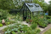 Serre moderne avec des potagers, des cages à fruits, des pots de forçage et des allées de dalles dans une zone en contrebas au-delà de la pelouse - Journée des jardins ouverts, Tuddenham, Suffolk