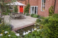 Cour-jardin avec dallage en grès, salon de jardin et petite pièce d'eau bordée de briques avec fontaines à bulles