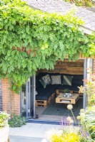 Maison d'été au bout du jardin avec glycine poussant autour du mur avant