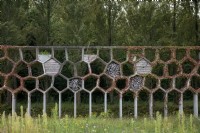 Jardin doté d'une pergola en nid d'abeille recouverte de lierre Maximapark aux Pays-Bas. Vieux bois placé dans les nids d’abeilles pour fournir un habitat aux insectes.