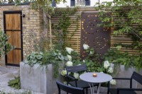 Jardin de cour au crépuscule avec parterres de fleurs surélevés et clôture en bois contemporaine avec écran et éclairage métalliques
