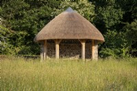 L'abri du verger de Rosemoor Gardens, RHS, Devon, un bâtiment de style grange traditionnelle au toit de chaume surplombant les vergers de pommiers.
