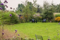 Chaises noires 'Airondack' pour enfants sur pelouse et parterres de fleurs de fin d'été
