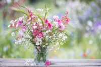 Bouquet de fleurs contenant Gypsophila elegans 'Covent Garden', Centaurea cyanus - rose, Delphinium 'Salmon Spire', Hordeum jubatum et Lathyrus 'Painted Lady' - Pois de senteur dans un vase en verre