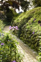 Chemin en briques longeant la limite du jardin formé par une colline fortifiée de l'âge du fer.