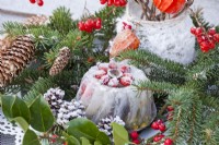 Arrangement hivernal avec gâteau glacé, branches d'épinette et bouquet de lanternes chinoises et brindilles de rose de Gueldre avec baies.