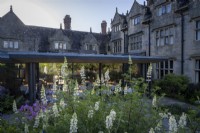 Les jardins du Gravetye Manor, avec Lupinus 'Noble Maiden' dans un petit parterre de fleurs à l'extérieur du restaurant