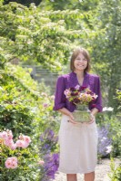 Femme portant un bouquet de fleurs dans un grand vase en verre