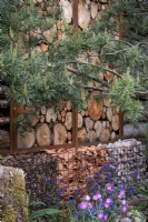 Mur en rondins avec gabions remplis de pots cassés, de pierres et de feuilles rassemblées