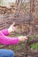 Femme tissant des bâtons de bouleau en cercle pour aider à maintenir ouvert le perchoir à oiseaux
