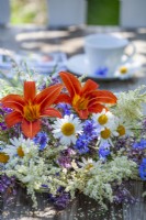 Bouquet de fleurs d'été contenant des marguerites, des bleuets, des hémérocalles, des grandes vergerettes et des persicaires.