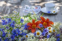 Bouquet de fleurs d'été contenant des marguerites, des bleuets, des hémérocalles, des grandes vergerettes et des persicaires.