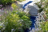 Un ruisseau d'eau moderne et contemporain avec une plantation mixte de plantes vivaces d'Euphorbia, de Geranium pratense 'Mrs Kendall Clark' et de Lychnis flos-cuculi 'White Robin'