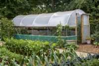 Potager cultivant des poireaux, du chou frisé, du céleri, des plants de blettes en rangées, un tunnel en polyéthylène, un jardin de démonstration d'attribution sans fouille