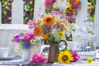 Bouquet d'été en porcelaine et pichets en métal composé de Dahlia, Daucus carota, Helianthus, Calendula, Allium, Hortensia, Pois de senteur et Nigelle. 