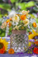 Bouquet de fleurs annuel composé de capucine, de souci, de carotte sauvage et d'amour dans une brume dans un bocal en verre décoré de ficelle. 