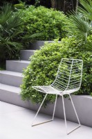 Chaise de jardin en métal blanc sur zone pavée à côté des marches 