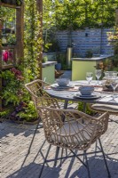 Le coin repas avec table et chaises est entouré d'une pergola en bois avec Trachelospermum jasminoides - Jasmin étoilé, heuchères et fougères. Coin avec foyer à l'arrière. Créateur : Colm Carty 