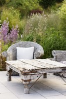 Vieille table en bois avec sièges en osier dans un jardin de juillet 