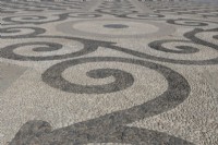 Un grand espace ouvert et plat est pavé de galets noirs et blancs et aménagé selon un motif symétrique et géométrique. Plaza de España, Parque de Maria Luisa, Séville, Espagne. Septembre 