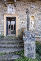 Entrée du cloître encadrée par diverses sculptures, dont des lions lombards du XIIIe siècle au manoir d'Iford 