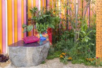 Un banc en pierre, un vieux baril de pétrole peint planté de légumes, d'herbes et de fleurs et un parterre de fleurs vivaces. Le RHS et Eastern Eye Garden of Unity, concepteur : Manoj Malde 