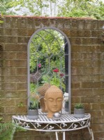Table et miroir en fer forgé contre un mur de briques dans le jardin du cottage 