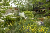 RHS Chelsea Flower Show 2023 - Le jardin RSPCA conçu par Martyn Wilson Silver Gilt, au premier plan Viburnum plicatum Watanabe avec des boutons d'or au-delà d'un coin salon 