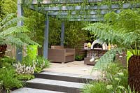 Terrasse avec pergola et fougères arborescentes, bambou canne doré, petite pervenche, Dicksonia antarctica, Phyllostachys aurea, Vinca minor Alba 