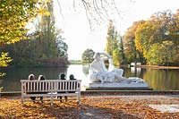 Visiteurs sur un banc au bord du lac et statue représentant le Père Danube 