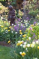 Sculpture entourée de Tulipa Yellow Pomponette, Tulipa viridiflora Spring Green, Tulipa White Heart, Lunaria annua 