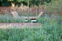 Jardin naturel avec chaise longue en bois, Stipa gigantea, Panicum Heavy Metal, Verbena bonariensis 