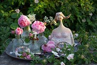 Décoration avec un buste de jeune fille et des roses dans des vases en verre 