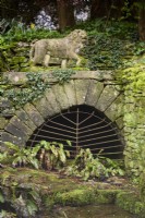 Grille métallique sous un lion de pierre dans les jardins de Cerney House en mars 