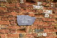 Panneau en ardoise accroché à un mur de briques à Cerney House Gardens en mars 