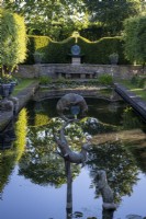 Des sculptures ornementales de loutres de Susie Wilson s'ébattent au-dessus d'un étang à la française qui reflète le jardin à la française environnant. 