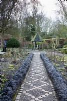 Chemin de gravier avec motif en losange de pavés bordé d'Ophiopogon planiscapus 'Nigrescens' au York Gate Garden en février 