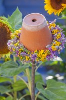 Pot de fleurs retourné avec une couronne de fleurs d'été dont Allium, Agastache et Tanacetum vulgare. 
