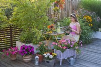 Terrasse d'été colorée avec des fleurs annuelles en pots, une fille aime lire un magazine. 