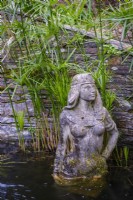 Statue égyptienne de Cléopâtre dans un étang tranquille avec des plantes aquatiques Papyrus 