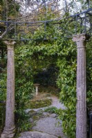 Deux piliers en pierre, faisant partie d'un temple de style classique donnant sur un jardin semi-tropical luxuriant 