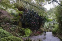 Lanterne japonaise en pierre dans un jardin caché sous les fougères et les camélias' 