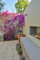 Un coin dans le patio avec des Bougainvilliers spectabilis en fleurs grimpant sur le mur et la cheminée dans le jardin méditerranéen. JuinDesigner : Alan Rudden 